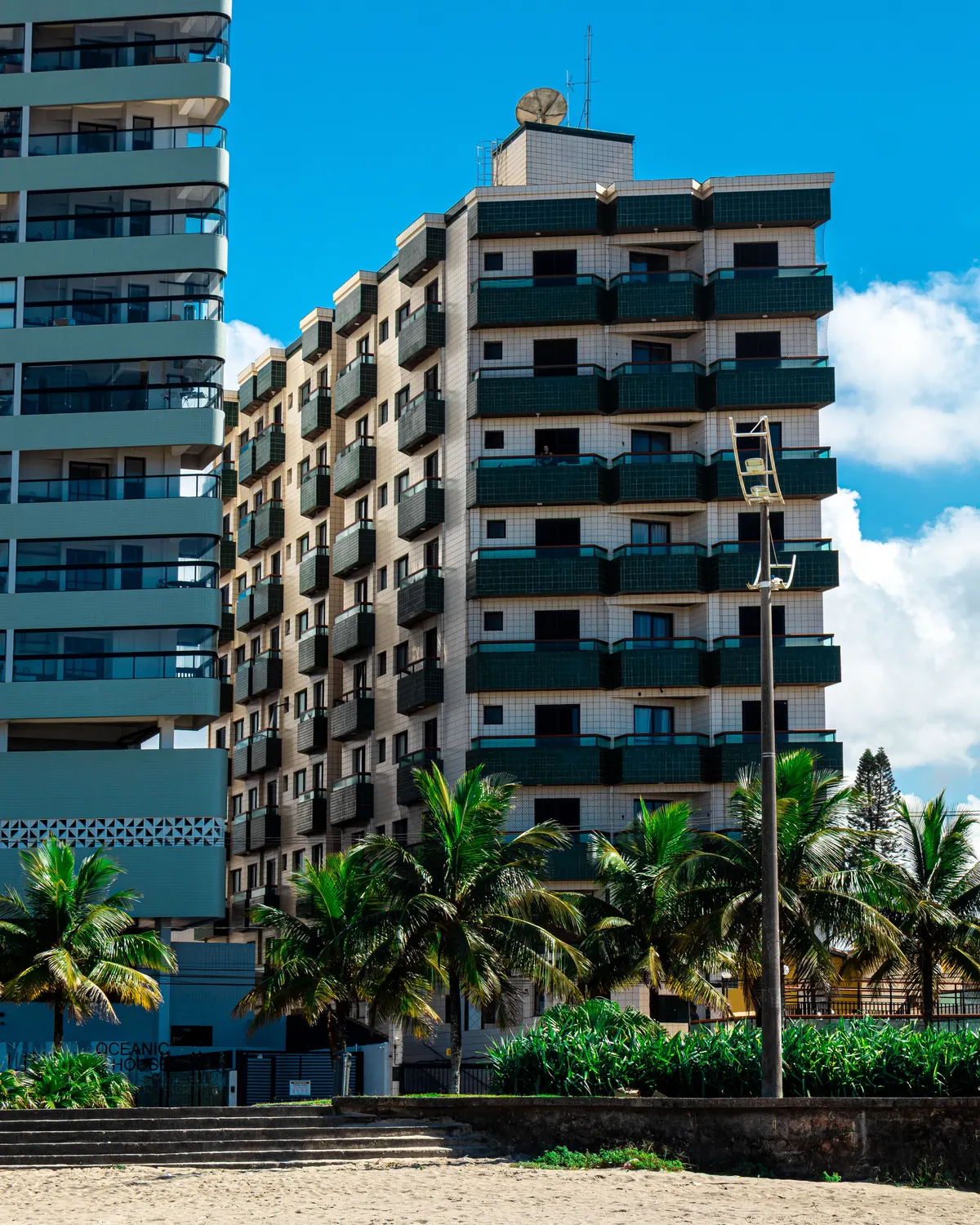 Prédios residenciais na orla de Praia Grande, com palmeiras.